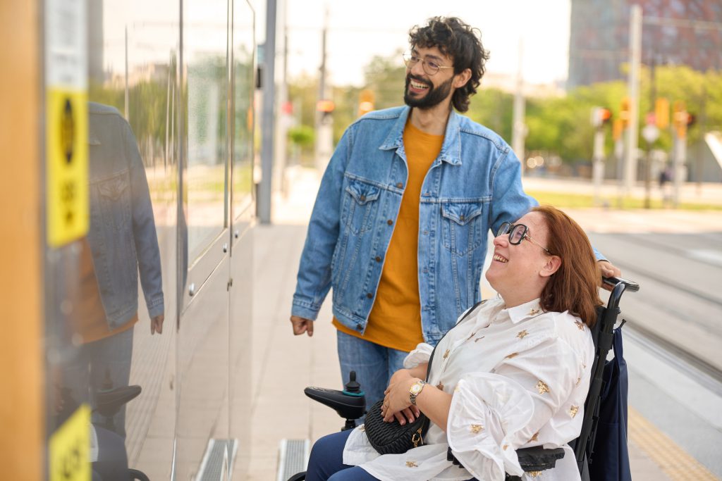 Un aidant accompagne une femme en fauteuil roulant dans les transports en commun